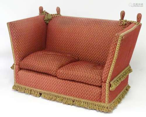 An early 20thC knoll sofa with drop ends, upholstered donkeys ears and ties terminating in