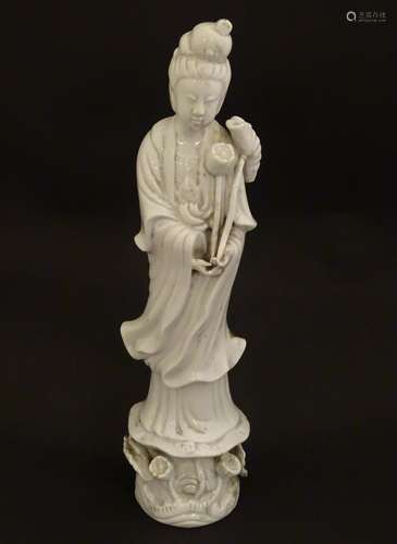 A Chinese blanc de chine figure of Guanyin holding flowers, raised on a base of lotus flowers and