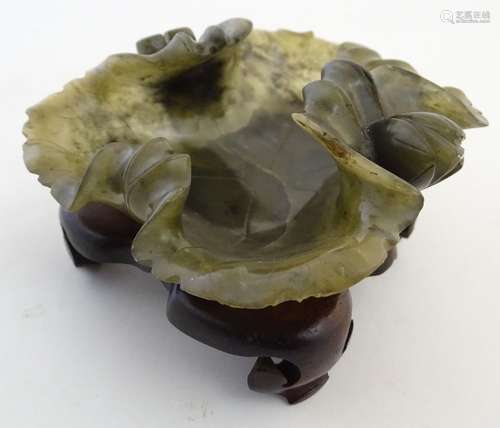 An Oriental carved spinach jade dish formed as a lotus leaf on a fitted stand. Approx. 2 3/4