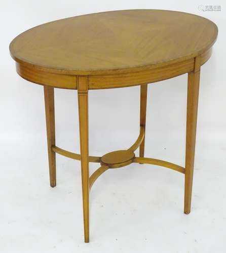 An early 19thc satinwood occasional table with an oval crossbanded top above four tapering legs