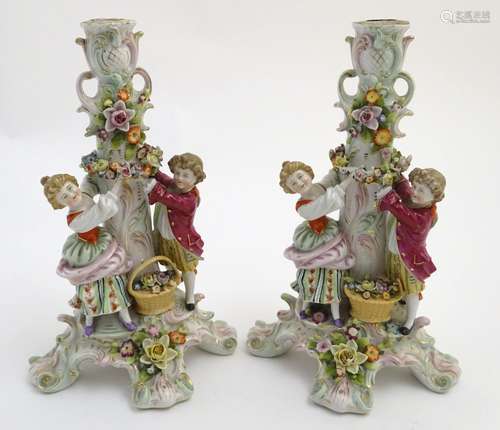 A pair of 19thC German figural lamp bases with two figures arranging flowers, raised on a