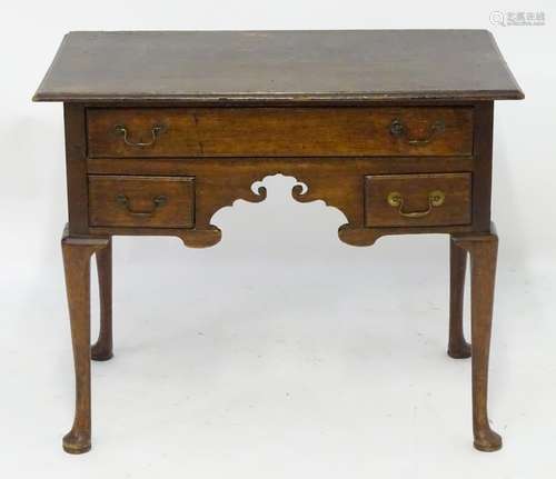 A mid 18thc oak lowboy with a moulded rectangular top above a single long and two short drawers with