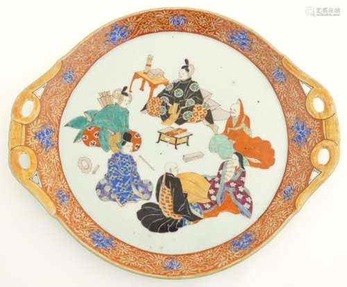 A Japanese twin handled plate with hand painted decoration depicting six seated figures with