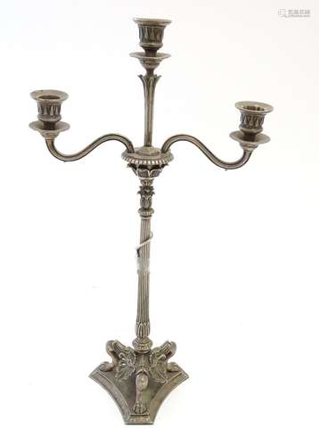 A Victorian silver plate three branch candelabra, with engraved armorial to base, lion's paw feet,