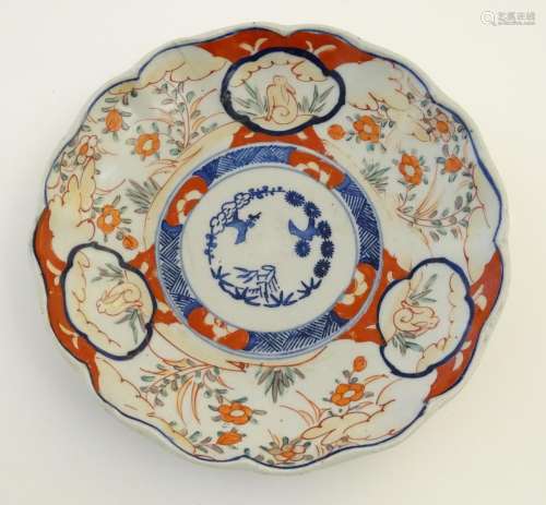 An Imari style plate with a lobed rim, decorated with floral and foliate scenes with panelled