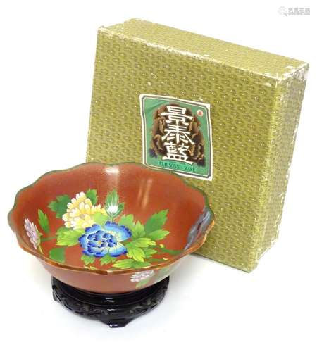 A Chinese cloisonne ware bowl with a lobed rim, decorated with flowers and butterflies, on a