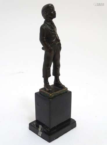 A 20thC bronze sculpture modelled as a young boy whistling with his hands in his pockets, on a