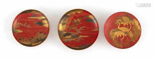 Drei Sakeschalen aus Lack mit Rotlackfond, in Goldlacktönen Reiher bzw. Landschaftsdekor