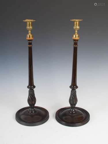 A pair of George III style mahogany and brass candlesticks, the brass urn shaped nozzles with