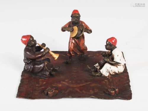 Franz Bergman - A cold painted bronze figure group of three boy musicians on a fringed carpet,