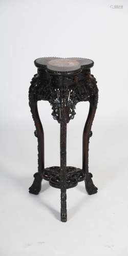 A Chinese dark wood urn stand, Qing Dynasty, the trefoil shaped top centred with a circular marble