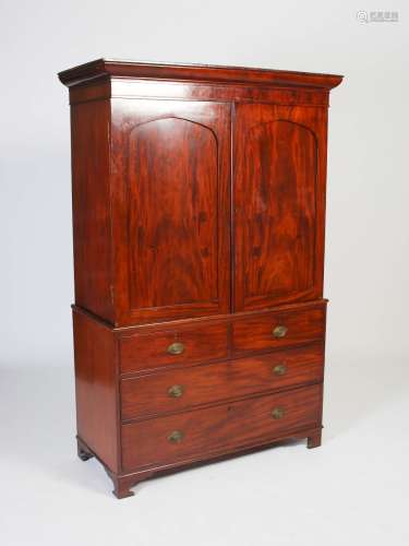 A George III mahogany linen press, the plain cornice above a pair of arched panelled doors,