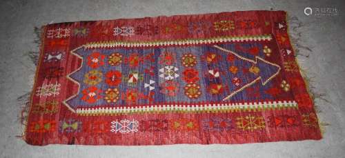 A Kelim rug, 20th century, the abrashed blue ground decorated with stylised flower head motifs,