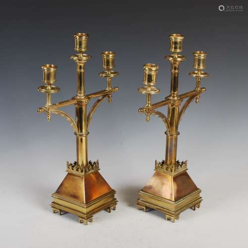 A pair of 19th century Gothic Revival brass three light candelabra, with urn shaped nozzles
