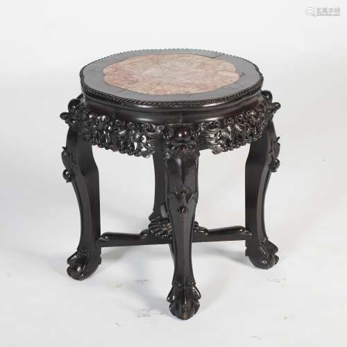 A Chinese dark wood urn stand, Qing Dynasty, the shaped circular top with a mottled red and white