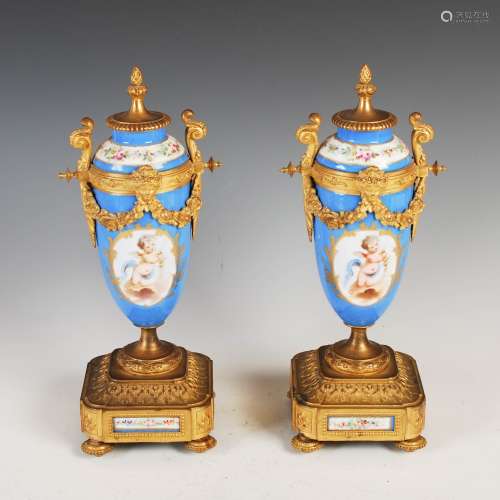 A pair of late 19th century Sevres style porcelain gilt metal mounted twin handled urns, the bleu