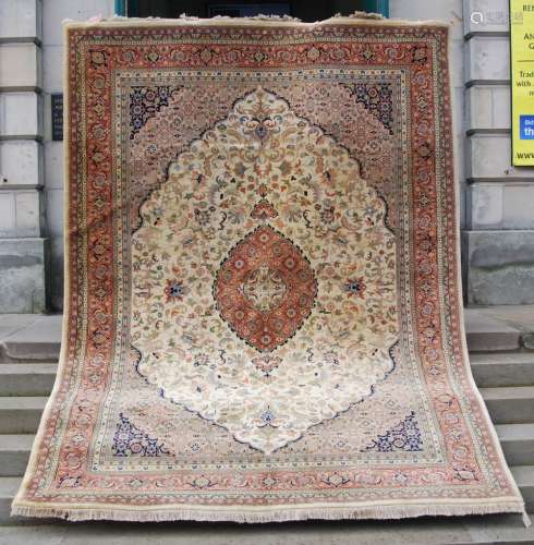 A Persian carpet, 20th century, the off white ground centred with a madder ground oval shaped