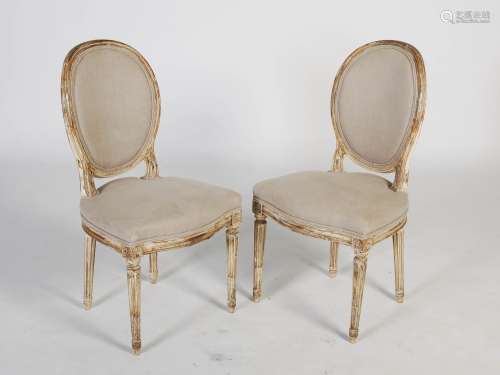 A pair of white painted beech wood side chairs in the French style, the oval upholstered backs and