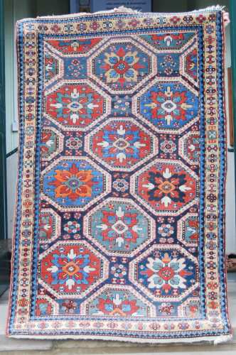 A Kazak rug, late 19th century, the dark blue rectangular field centred with nine octagonal shaped