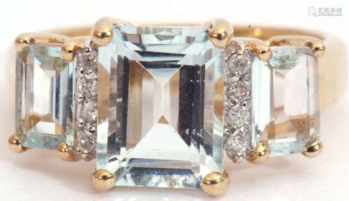 9ct gold pale blue stone and diamond ring, a design with three graduated emerald cut pale blue