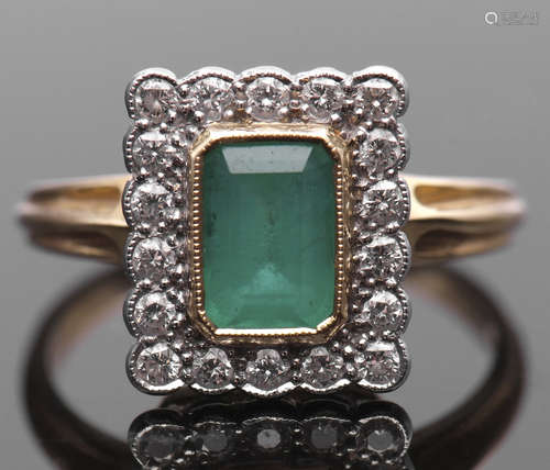 Emerald and diamond cluster ring, the rectangular step cut emerald bezel set and millegrained edged,