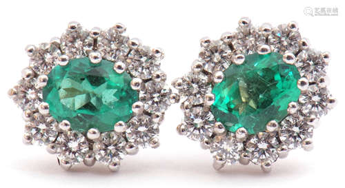 Pair of emerald and diamond cluster earrings featuring an oval emerald, 1.15ct total, each within