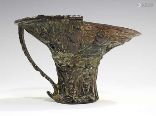 A Chinese horn libation cup, 20th century, carved in relief with figures amidst pine, height 10.