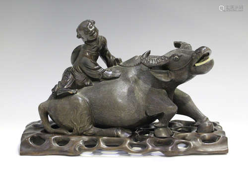 A Chinese carved hardwood figure group of a boy seated on the back of a recumbent water buffalo,