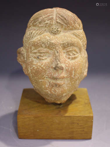 An Indian terracotta head, probably Gupta period, 6th century, modelled with hair tied, height 12.