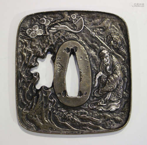 A Japanese brown patinated bronze tsuba with silver inlaid decoration, one side cast in relief