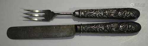 A Chinese silver child's knife and fork, early 20th century, each handle decorated in relief with