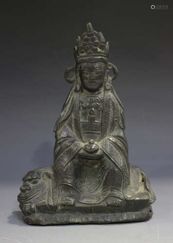 A Chinese cast bronze figure of Guanyin, probably Ming dynasty, modelled seated on the back of a