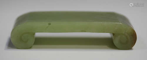 A Chinese jade brush rest, early 20th century, of scroll form, the stone of celadon green tone