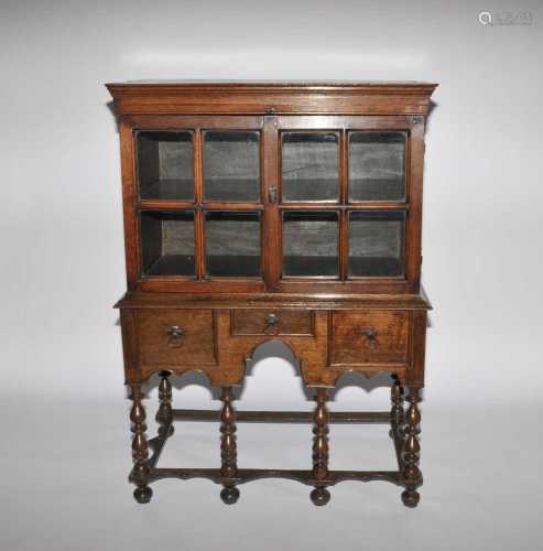 A c1700 and later oak cabinet on an associated stand with three frieze drawers above a shaped apron,