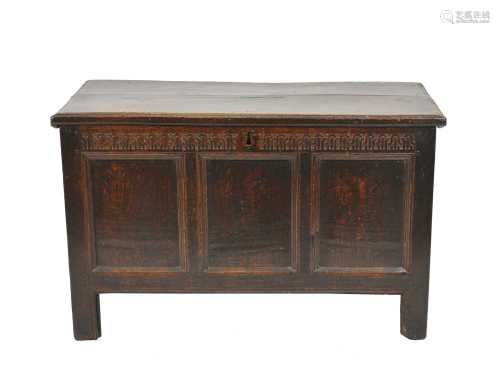 A late 17th century oak coffer, the twin plank top above a chain carved frieze with three panels