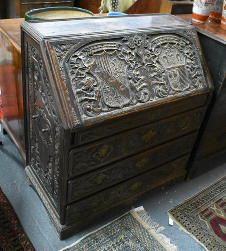 An antique oak bureau, profusely relief carved