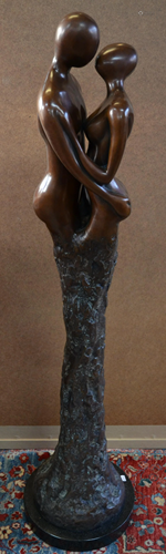 A brown bronze figural sculpture of a kissing couple