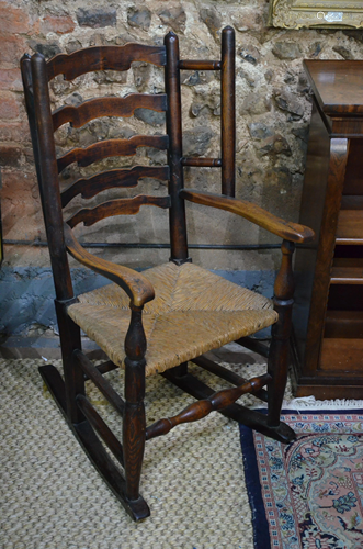 An 18th century oak ladder back rocking armchair