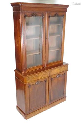 A mid 19thC glazed mahogany bookcase with a moulded cornice above four shelves. The glazed doors