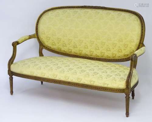 An early 20thC sofa with a carved giltwood frame and upholstered back rest and seat above four