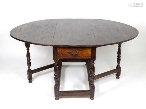 An 18thC oak drop leaf table opening to form an oval table top, the table having a single frieze