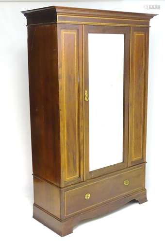 An early 20thC mahogany wardrobe with a moulded cornice above a central mirrored door and a single