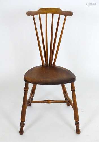 An early 20thC Windsor chair with a comb back and an elm saddle seat, that chair raised on turned