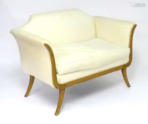 A 20thC sofa with a shaped backrest and swept arms and legs with carved and inlaid decoration. 49