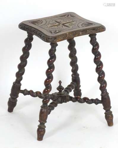 A late 19thC / early 20thC oak stool with floral carvings to the shaped top and standing on four