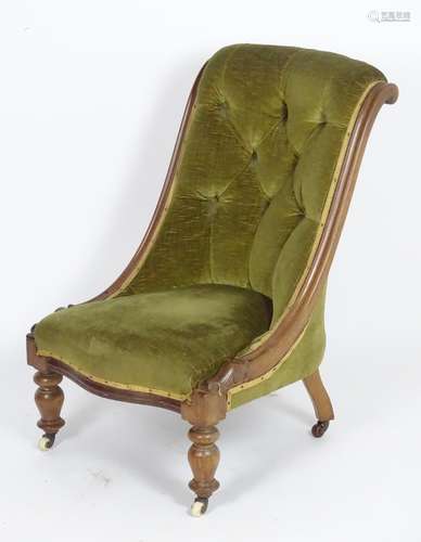 A late 19thC / early 20thC nursing chair with a deep buttoned backrest and raised on turned tapering