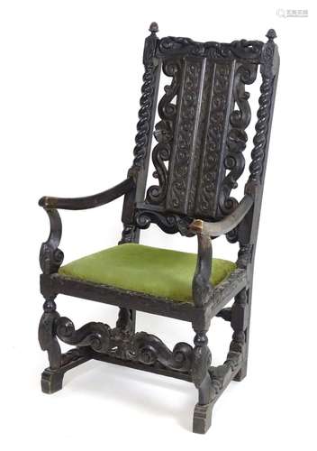 A 19thC carved ebonised open armchair with scrolled decoration and barley twists supports above a