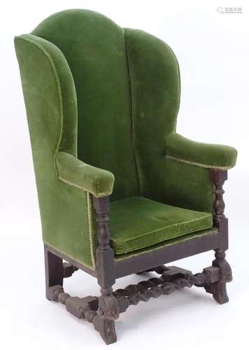 An 18thC wing back armchair with carved legs united by a turned H stretcher. 45