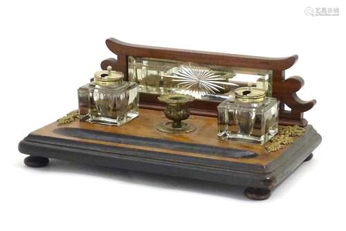 A Victorian desk standish with a central taper stick flanked by two glass inkwells, the base with