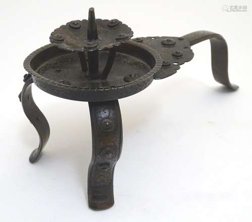 A Japanese bronze candle stand with a raised sconce, on three supports, with scrolling punchwork